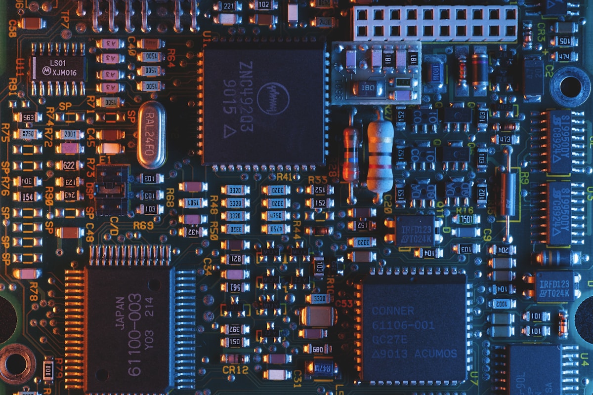 A close-up of a green silicon chip with its golden circuit traces visible.