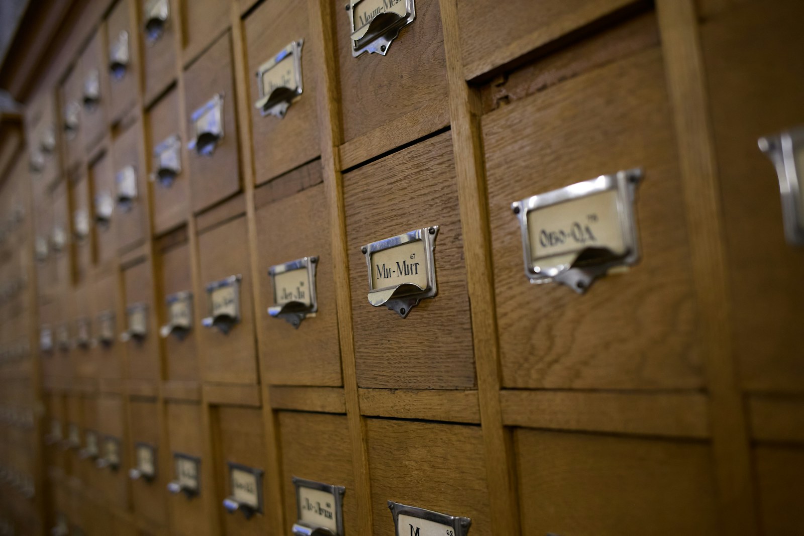 A wall of wooden card-catalog drawers in a library, each labelled with a numeric range.