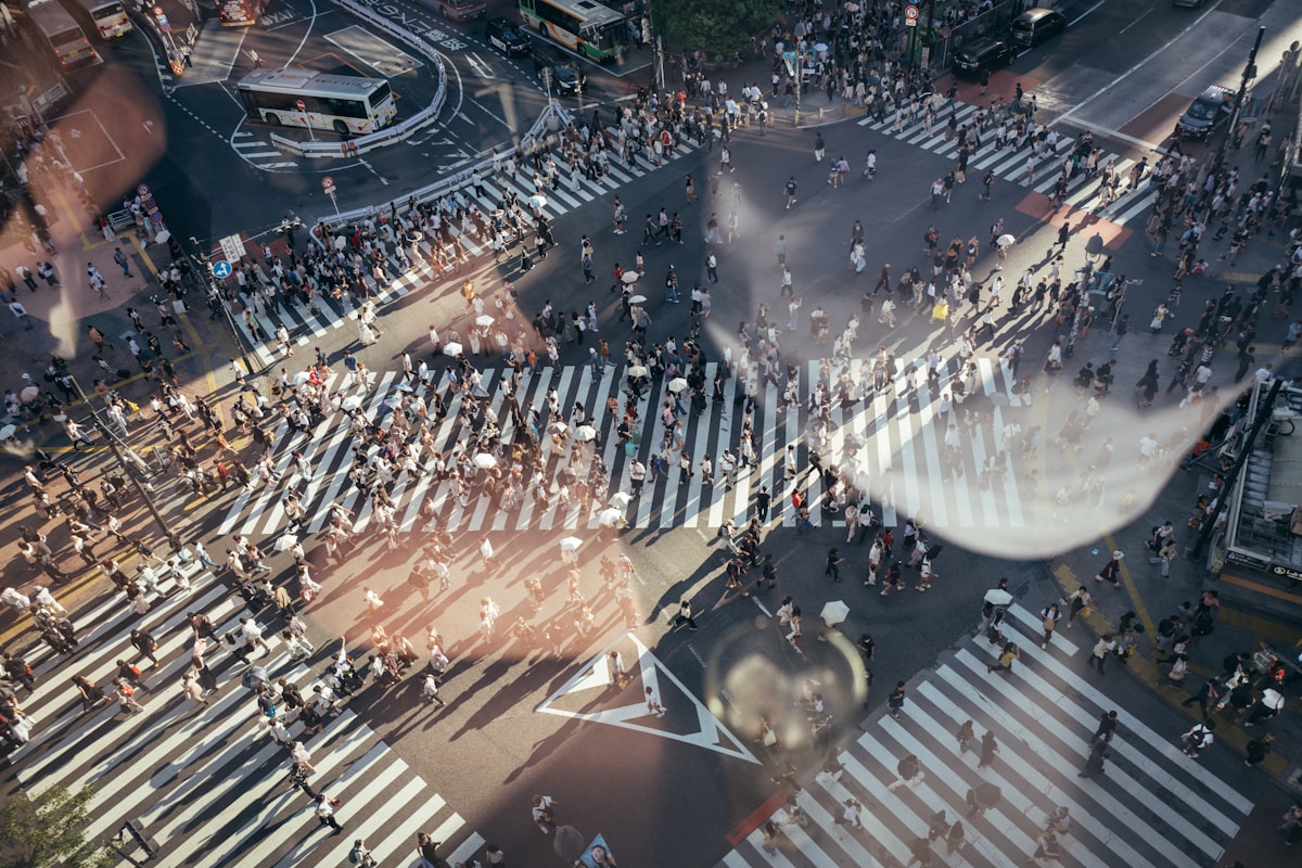A crowded intersection seen from above, with many people crossing in all directions.