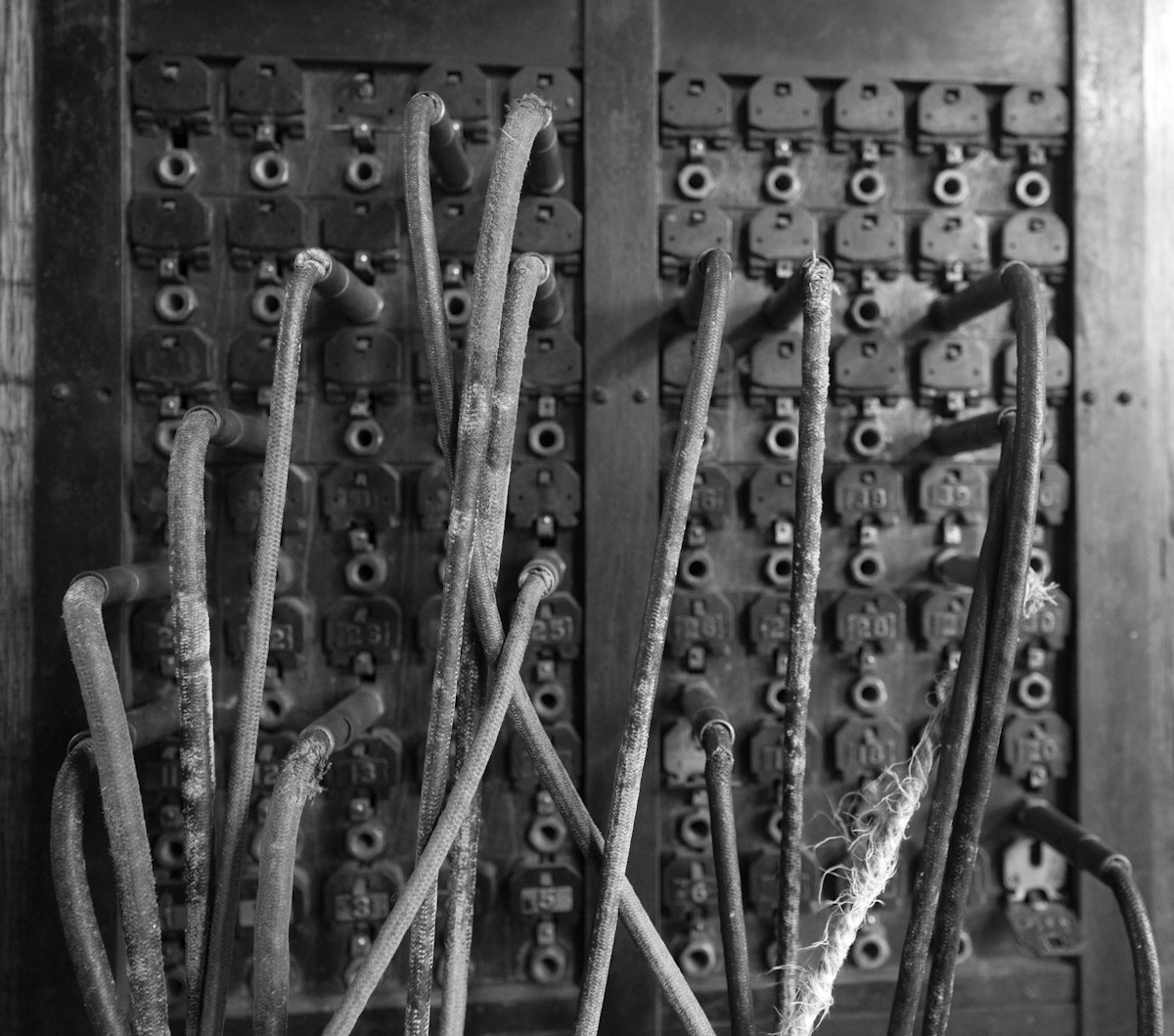 An old telephone switchboard with rows of brass jacks and tangled wiring.