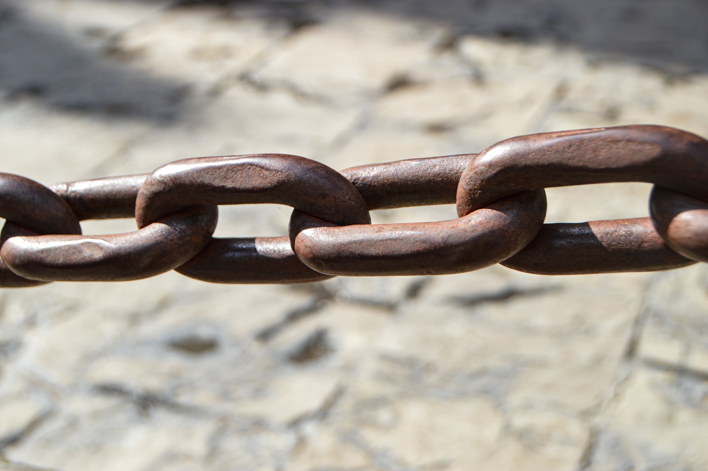 A close-up of a heavy metal chain on a stone surface.